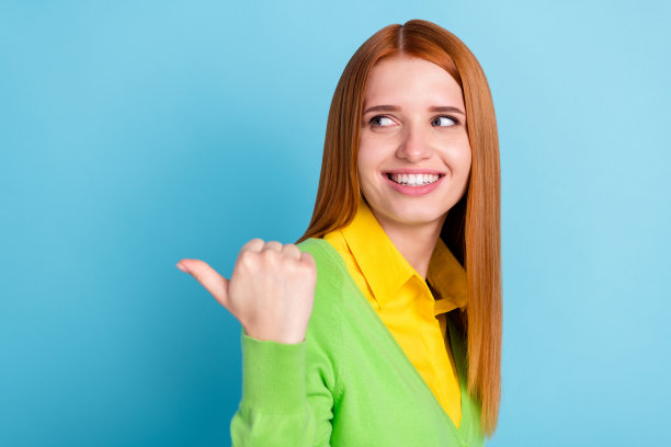 穿着黄色毛衣的甜美年轻女士的个人资料照片，指向蓝色背景上的空白空间图片下载