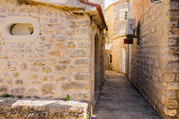 狭窄的巷道，两侧是石头墙壁和复古灯光，展现了夏日旅行、建筑魅力和欧洲历史街道的亲密感。图片下载