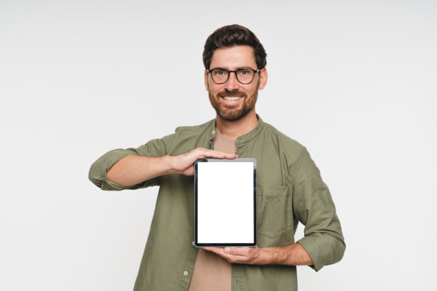戴眼镜的快乐男子，手持平板电脑，肖像照，带有用于广告或营销的样机屏幕，背景为白色工作室。男性展示技术显示屏或用于广告的样机空间。图片下载