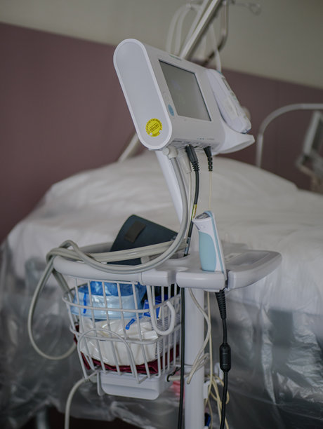 医院病房里，床边的病患监护仪推车上摆放着医疗线缆、耗材和诊断设备，展示了现代医疗保健技术和病人护理工具。专业照片。图片下载