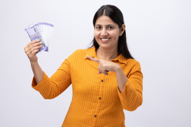 身穿黄色库尔塔服饰的中年印度女性展示印度卢比，纯白背景下的人物照片素材图片下载