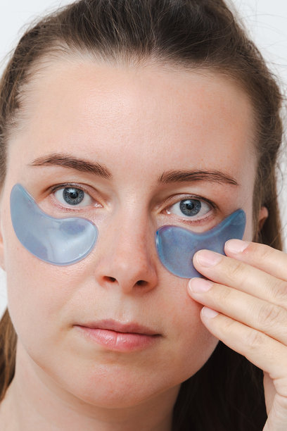 年轻的欧洲女性或女孩，眼部贴有皮肤贴片。自我护理、简约的概念，竖幅照片，特写图片下载