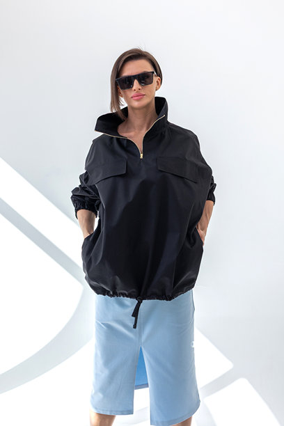 身穿黑色防风夹克和浅蓝色裙子的优雅女士，背景为白色。时尚女性风格。影棚摄影。竖幅照片图片下载