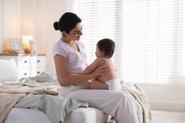 妈妈和她可爱的宝宝在床上的室内照片图片下载