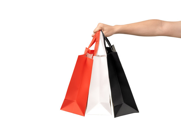 一只手提着有提带的纸质购物袋，背景干净的白色。工作室拍摄，有充足的复制空间用于文本、标志或品牌。白色孤立，抠出。图片下载