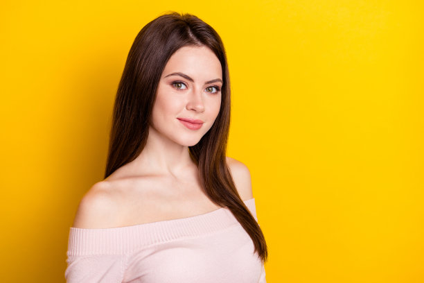 穿着粉色衬衫的乐观的金发女士，在黄色背景下拍摄的照片图片下载