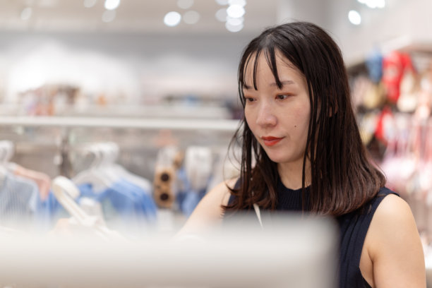 一位身穿黑色无袖连衣裙的孕妇在婴儿服装店购物图片下载