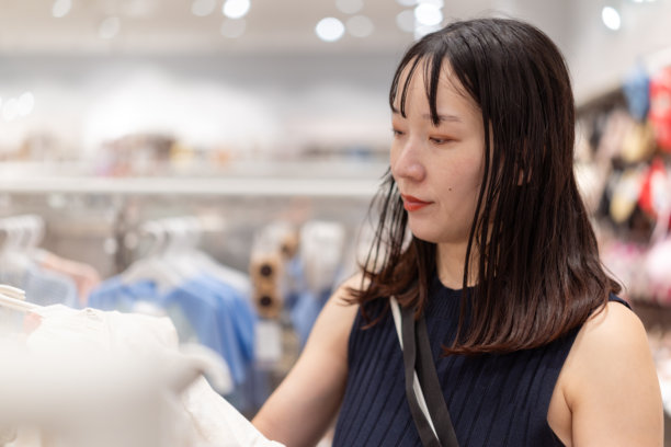 穿着黑色无袖连衣裙的孕妇在婴儿服装店购物图片下载