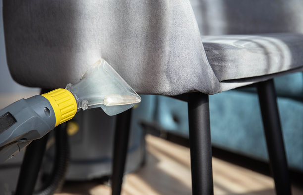 女孩的手用清洗吸尘器清洁公寓里布艺椅子的灰色内饰上的污垢。清洁服务，布艺家具清洁图片下载