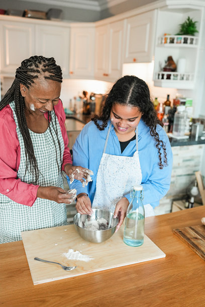 冬季假期，快乐的非洲母亲和女儿在家一起准备面包——一家人一起烹饪的女人——主要聚焦在妈妈的脸上——垂直照片图片下载