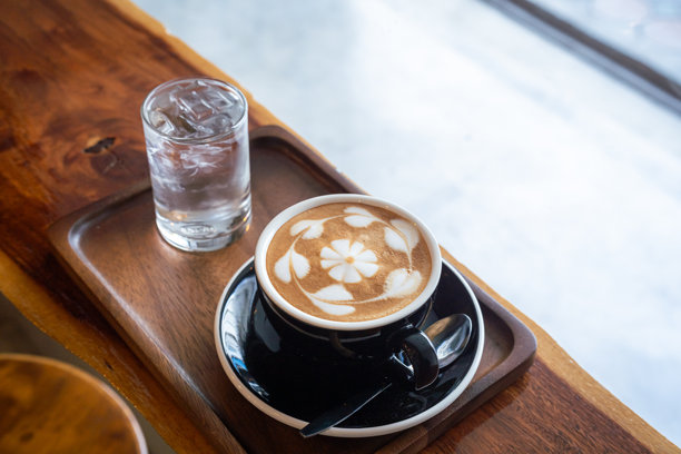 热咖啡拿铁，杯子上有拉花奶泡，搭配自制比利时华夫饼和蜂蜜，放在木桌上，俯视角度。作为咖啡馆的早餐，在工作期间。图片下载