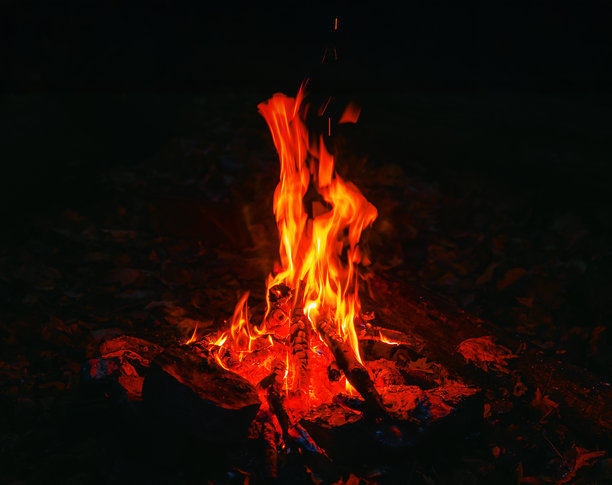 夜晚篝火熊熊燃烧，火舌明亮。篝火在黑暗中燃烧，伴有火星和火焰。图片下载