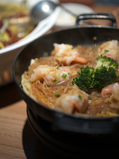 铸铁锅中的海鲜粉丝火锅，配有西兰花和虾图片下载