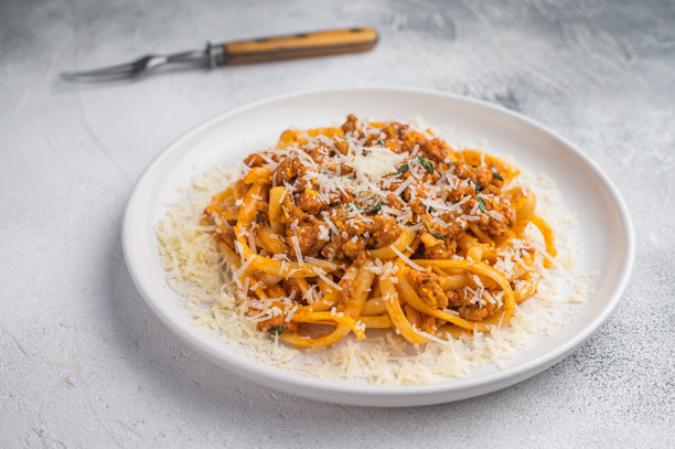 美味的肉酱意面撒上帕玛森芝士，置于纹理灰背景上，明亮干净的食物俯拍照片。图片下载
