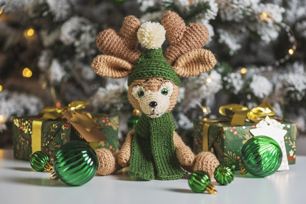 节日室内装饰：带礼物的钩针驯鹿和圣诞树图片下载