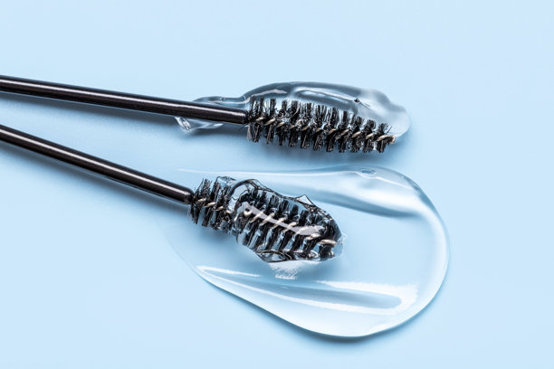 透明眉毛和睫毛精华液的特写照片，质地光滑闪亮，背景为蓝色图片下载