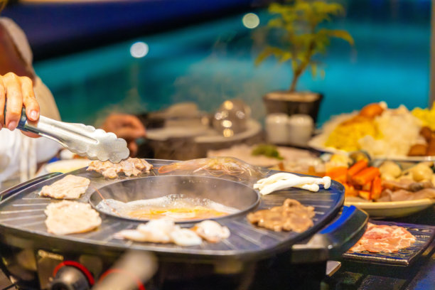亚洲火锅晚餐，烧烤架上的海鲜和蔬菜，有人在使用图片下载