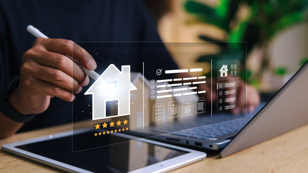 一个人使用带有虚拟房地产界面的数字平板电脑和笔记本电脑，界面包含房屋图标、评分星级、文件和房产清单。智能物业管理的理念。图片下载