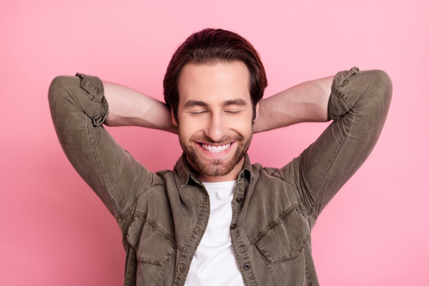 俯视镜头拍摄的年轻男子双手枕在脑后，在粉色背景上放松休息睡觉的照片图片下载