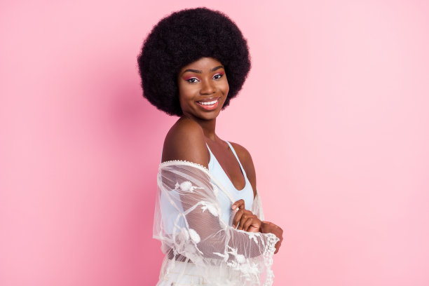 照片肖像：卷发女孩，笑容灿烂，身穿白色服装，背景是孤立的粉彩色调的粉色图片下载