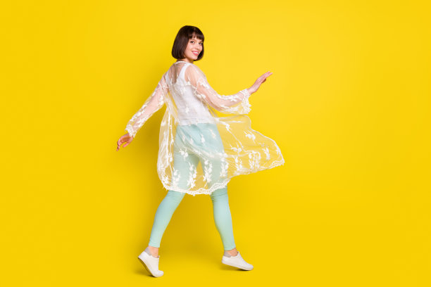 快乐迷人的年轻女子在夏季空旷的黄色背景前行走，全尺寸照片图片下载