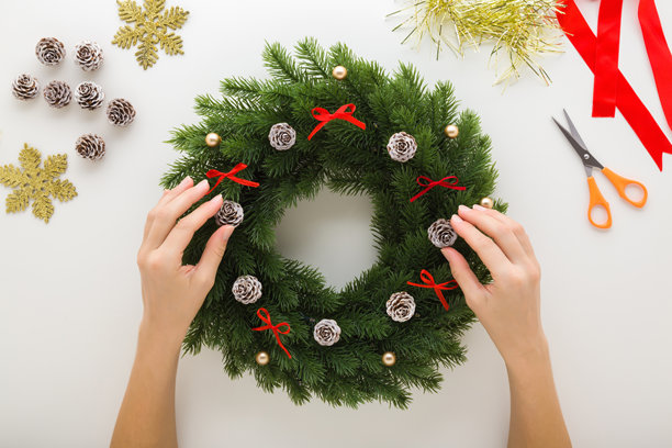 年轻女子手捧着绿色的冷杉枝，在浅灰色桌面上装饰，制作圣诞节门饰。特写镜头，第一人称视角，俯视角度。图片下载