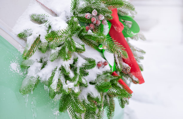 挂着丝带的节日圣诞花环装饰着雪天里的复古货车图片下载