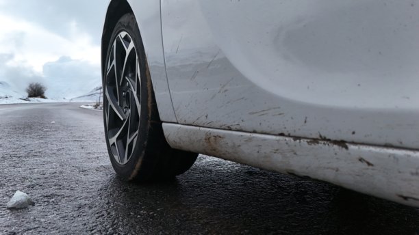 一辆肮脏的汽车和磨损的轮胎，它们已经驶离越野路段，上了沥青路。图片下载