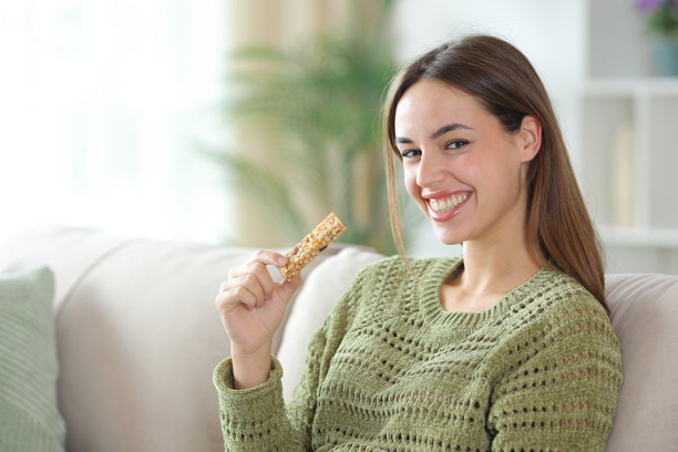 快乐的绿衣女子拿着谷物棒看着你图片下载