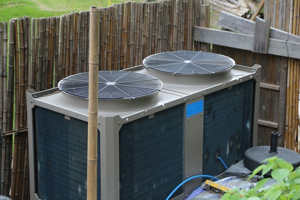 爱尔兰一栋房屋屋顶上安装的空气源热泵的超精细照片，后面是竹篱笆。图片下载