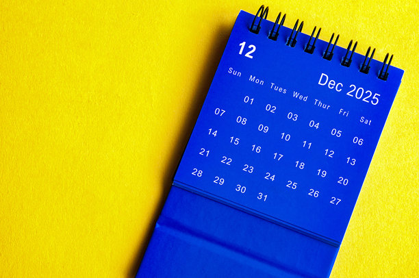 2025年12月蓝色台历俯视图，背景为黄色封面。十二月和年末概念。图片下载