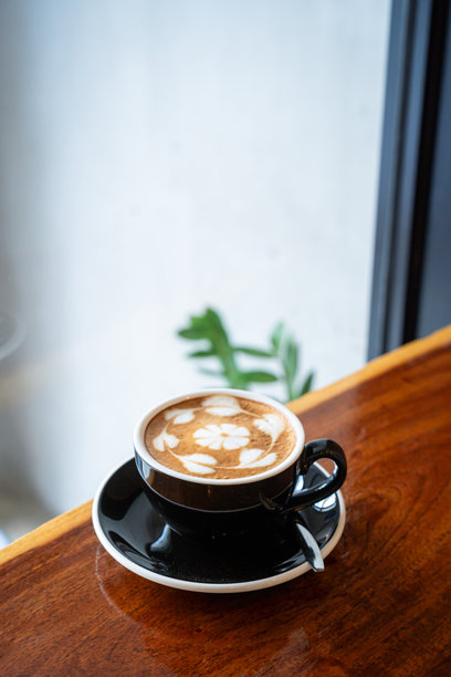 俯视角度，木质桌面上放着一杯带有拉花奶泡的热咖啡拿铁，作为咖啡馆的早餐，适合工作时饮用，复古风格。图片下载