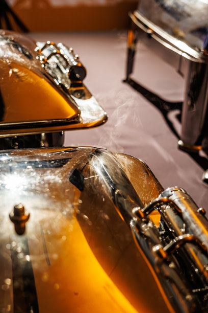 温暖灯光下，热气腾腾的不锈钢保温盘的细节视图，突出了其抛光表面和热量。非常适合餐饮服务或活动策划的视觉素材。图片下载