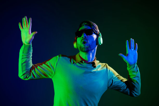 戴着耳机、眼镜和毛衣的年轻男子的照片，在深蓝色背景下跳舞歌唱图片下载