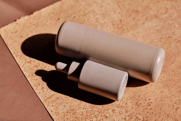 瓶装面部乳液和精华液，带有滴管，放在软木垫上。图片下载