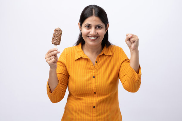 一名中年女性在白色背景下吃冰淇淋的照片图片下载