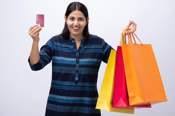 身穿蓝色库尔塔（kurta）的中年女性手持购物袋，白色背景下的照片素材图片下载