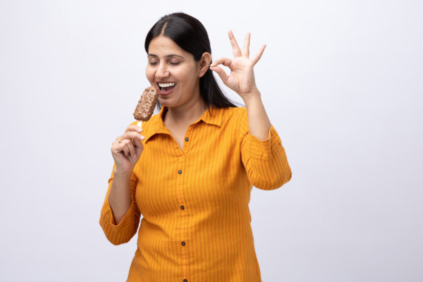 一名中年女性在白色背景上吃冰淇淋的图片素材图片下载