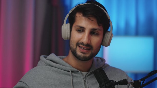 一位戴着耳机、快乐的西班牙裔拉丁裔男子正在现代家庭工作室里，使用专业麦克风录制播客，在采访中分享连接与欢笑的时刻，进行网红直播广播音频制作。图片下载