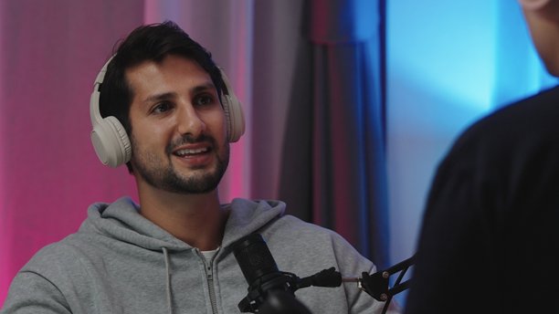 快乐的西班牙裔拉丁裔男子戴着耳机，在演播室与主持人一起录制播客，在采访中分享连接和欢笑的时刻，网红直播音频制作在现代家庭工作室图片下载