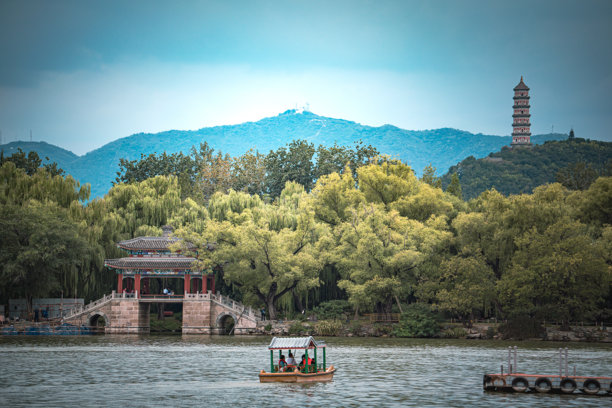 一座令人惊叹的夏季宫殿景象。图片捕捉了古老建筑的细节，坐落于宁静的湖泊和充满活力的绿植之间，背景是连绵的山峦。天空多云，光线 Perfect。图片下载