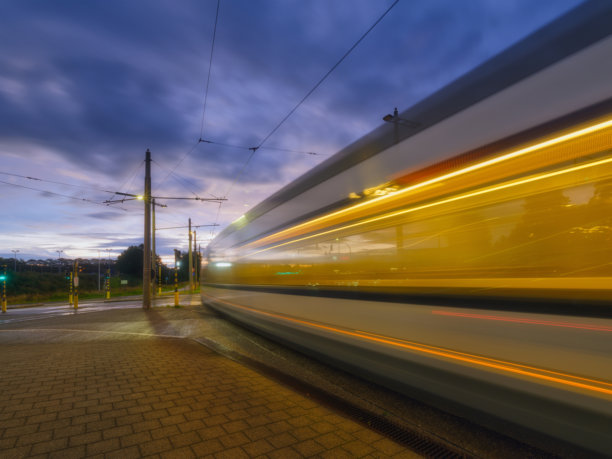 有轨电车站。公共交通和日落时的天空。有轨电车行驶时模糊的光线。交通运输。明信片、壁纸和背景照片。图片下载