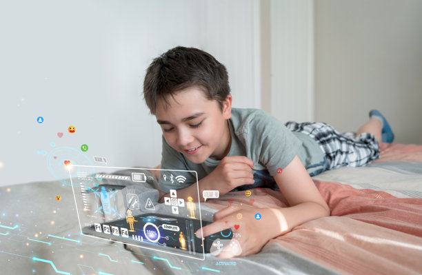 男孩躺在床上玩平板电脑，屏幕上叠加着未来感的游戏用户界面，概念涉及在线游戏、沉浸式技术、教育科技、数字生活方式以及青少年与技术的互动。图片下载
