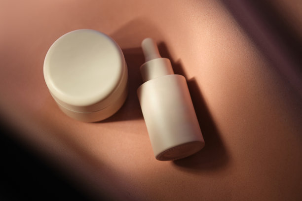 柔和米色背景上的面霜和精华液。图片下载