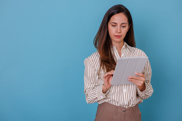 一位职业女性手持带有灰色封面的数码平板电脑，触摸屏幕并浏览内容图片下载