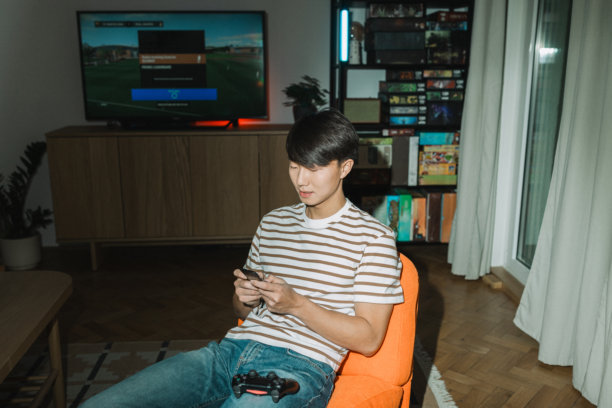 一个青少年在舒适的客厅里使用复古翻盖手机图片下载