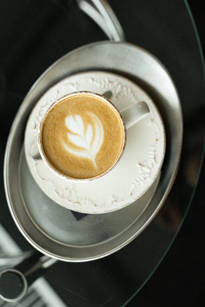 白色杯子里的拿铁咖啡拉花，放在托盘上图片下载