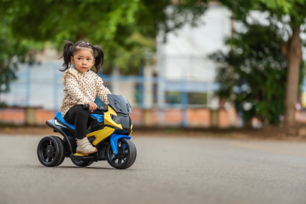 小女孩在公园里骑着电动玩具摩托车图片下载