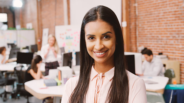 现代办公室里，一位面带微笑的年轻女商人在砖墙前摆出肖像照图片下载