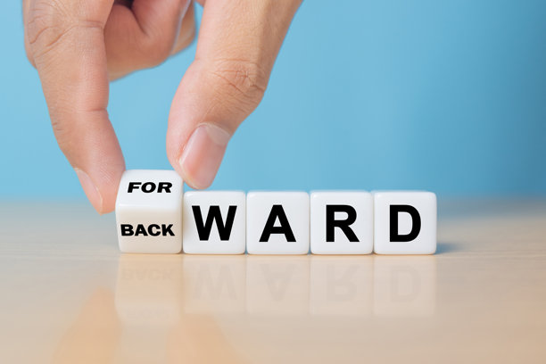 手转动立方体，将骰子上的“向后”字样改为“向前”。背景为漂亮的黄色桌面，白色背景，留有复制空间。图片下载